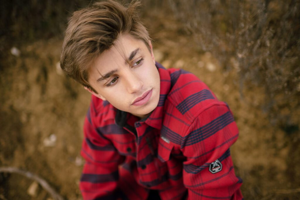 high school senior guy looks off camera wearing red and blue flannel