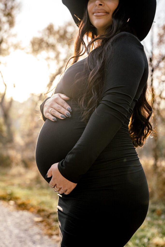 preganant belly with mother's hands on during golden hour maternity shoot.