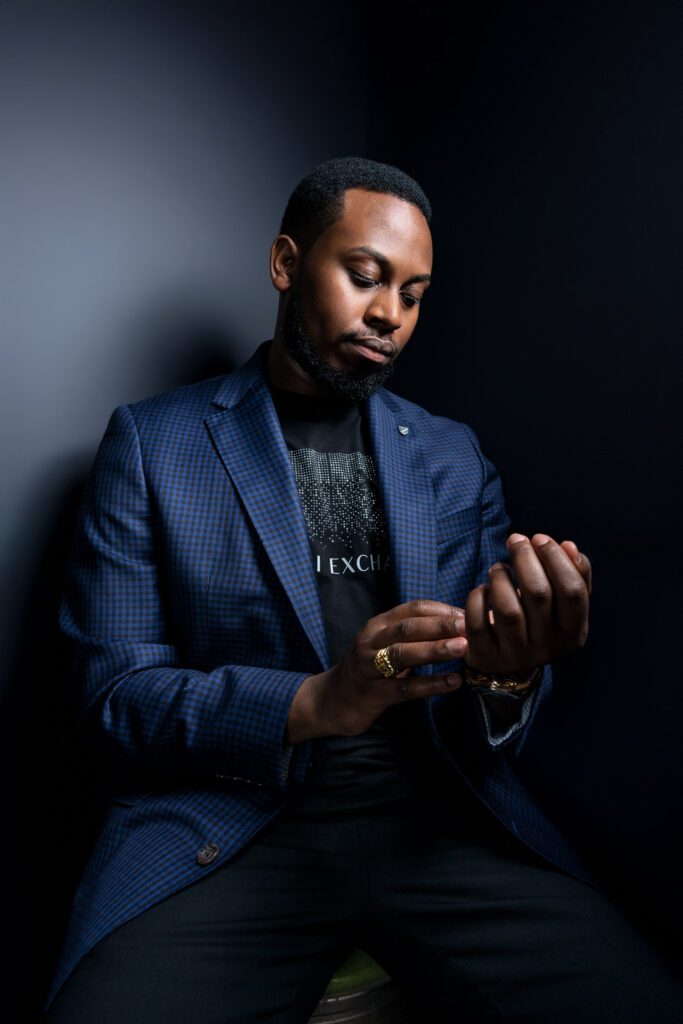 black male model adjusting watch wearing armani t shirt and blue jacket