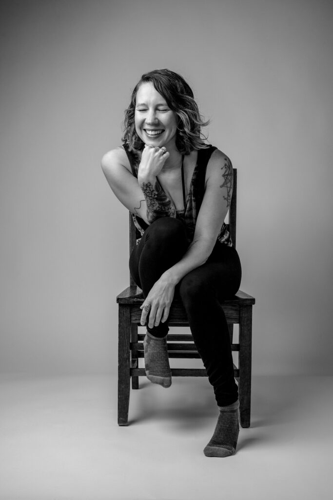 Woman laughing while sitting on brown wood chair for portrait
