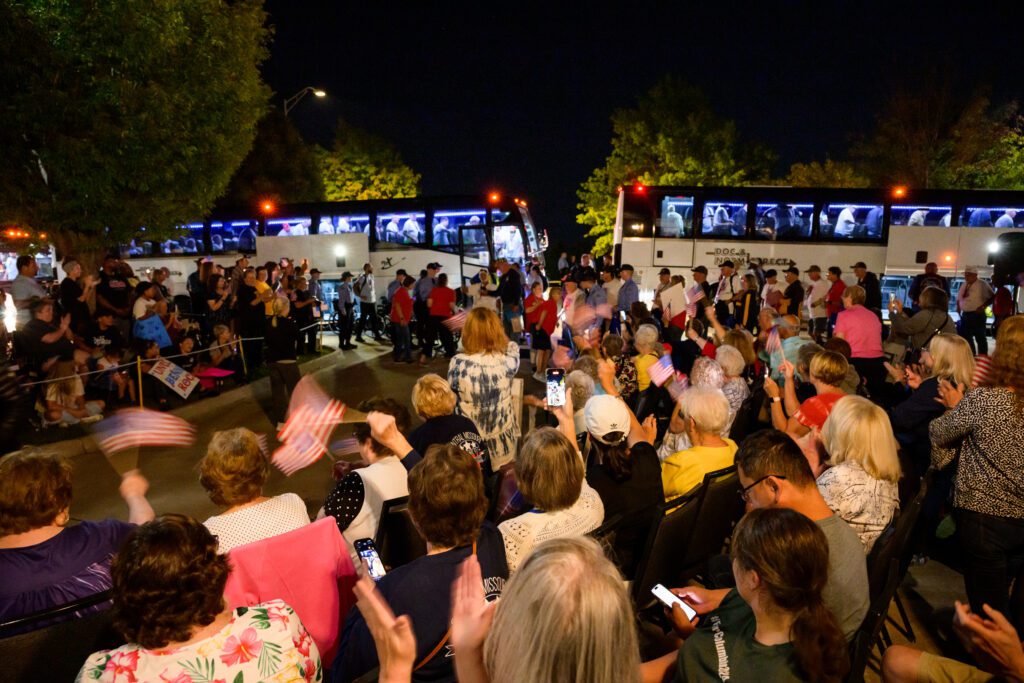 people clap hands as buses full of veterans arrive from honor flight